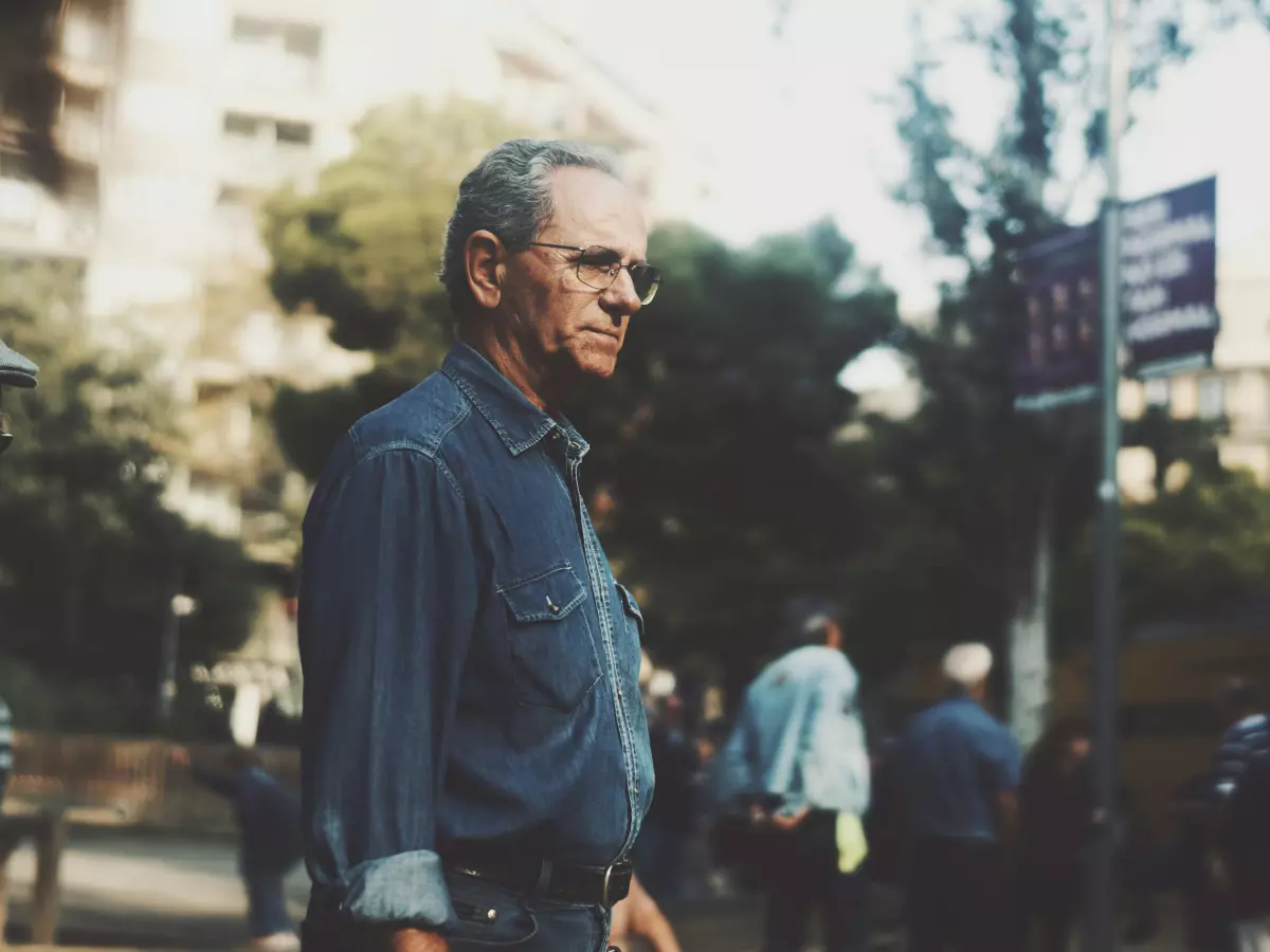 A middle-aged man in a blue shirt and jeans, walking through a busy city street