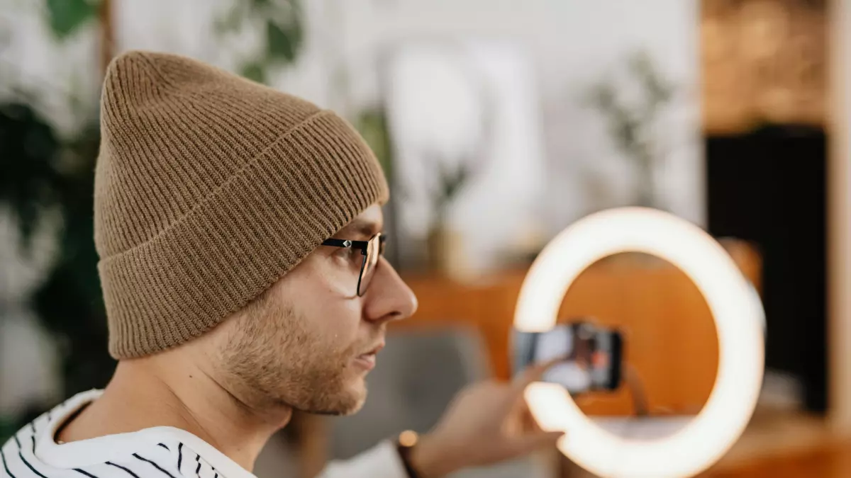 A person recording a video on their phone, they are using a ring light to illuminate their face.