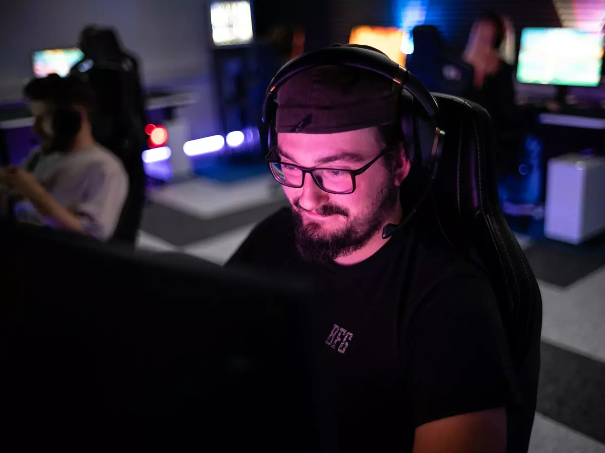 A young man wearing a headset and looking at a computer screen with a focused expression.