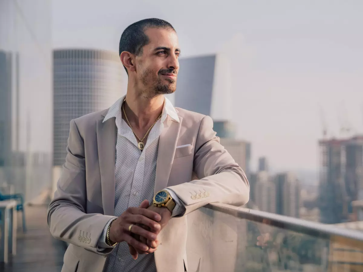 A businessman in a suit stands on a rooftop looking out over the city.