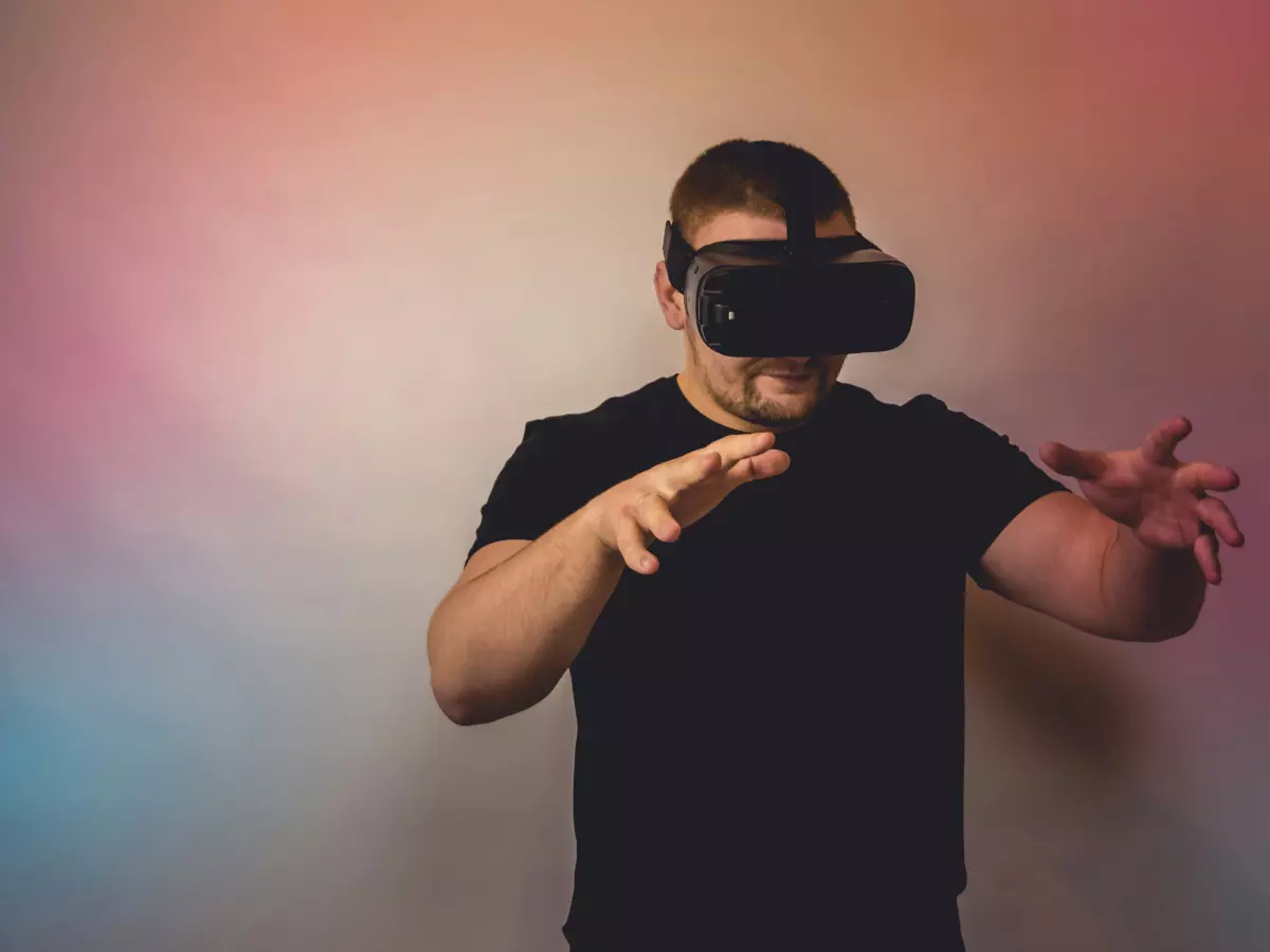 A man wearing a VR headset with a surprised expression on his face, gesturing with his hands as if interacting with something in the virtual world.