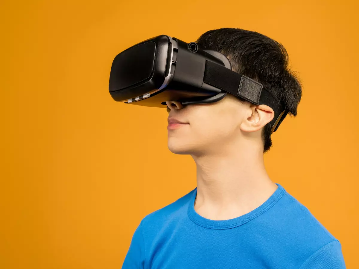 A young man wearing a blue shirt and a VR headset, on a yellow background