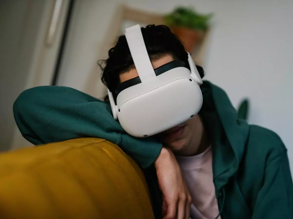 A person wearing a VR headset sits on a couch, with a focus on the headset.