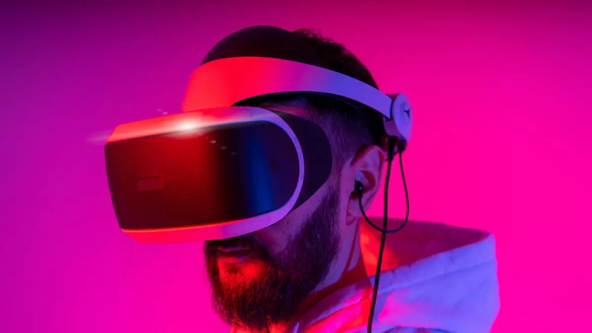 A person wearing a VR headset, with a dramatic lighting effect, in a pink and blue light, standing in a room.  