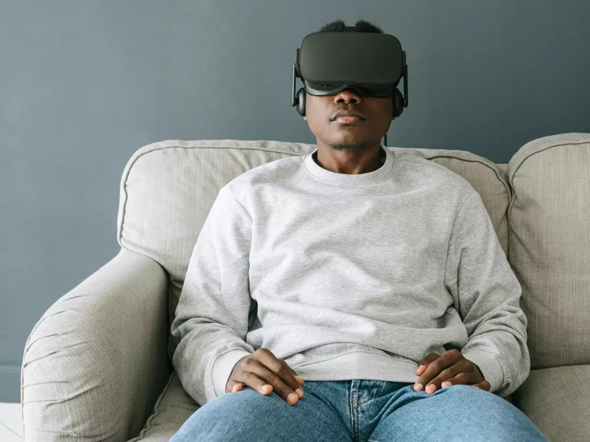 A person wearing a VR headset sits on a couch.