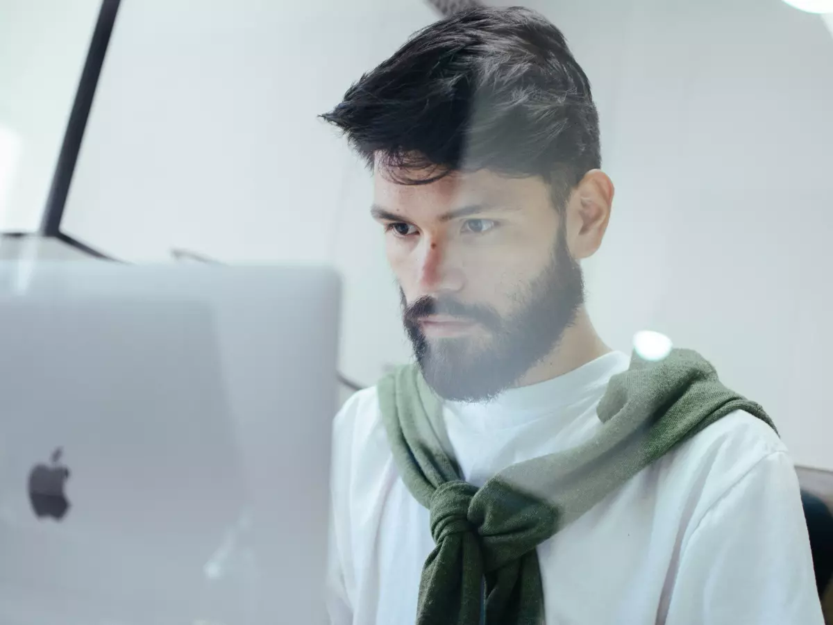 A man sits at a desk, looking intently at a laptop screen, a close-up of his focused face highlighting the potential danger he faces from a security flaw.