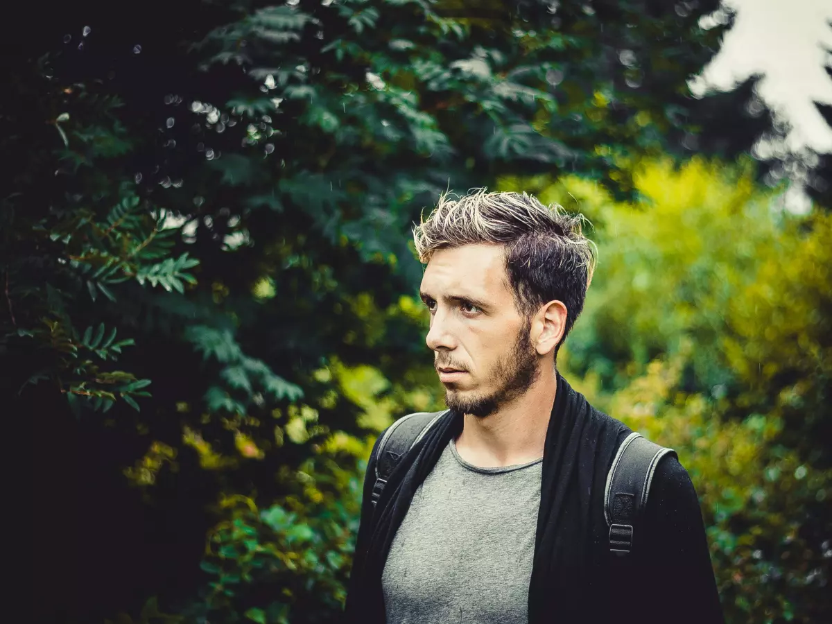 A young man with a backpack is using a smartphone.