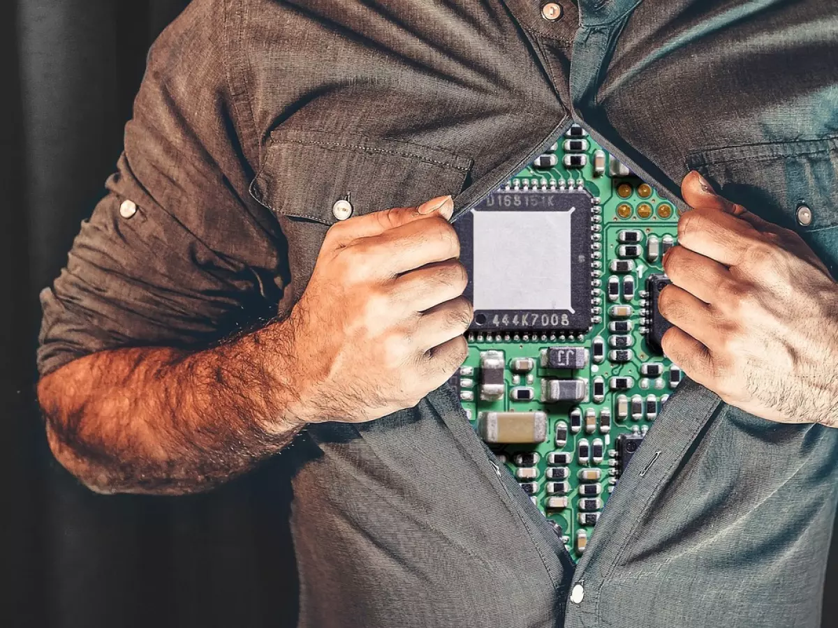 A man with a torn shirt revealing a circuit board, symbolizing the integration of technology within the human body. The image evokes a sense of wonder and mystery.