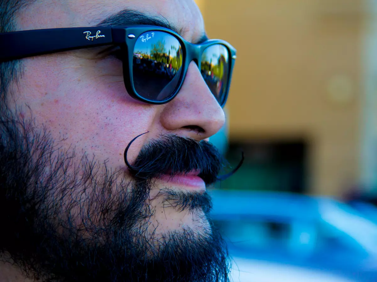 A man with a mustache and beard wearing sunglasses is shown from the nose up.