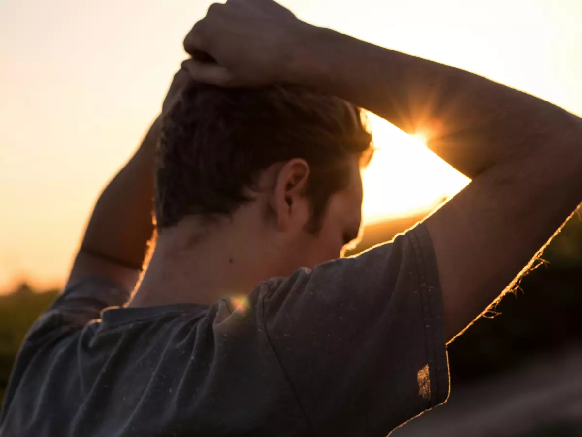 A person with their back to the camera, looking at the sunset.