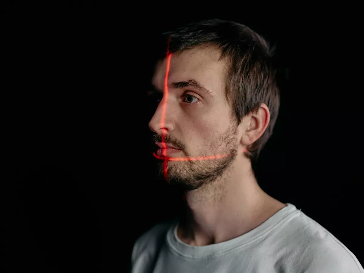 A man's face is half visible, with a red line separating the visible and invisible halves, the image is suggestive of an anonymization process.