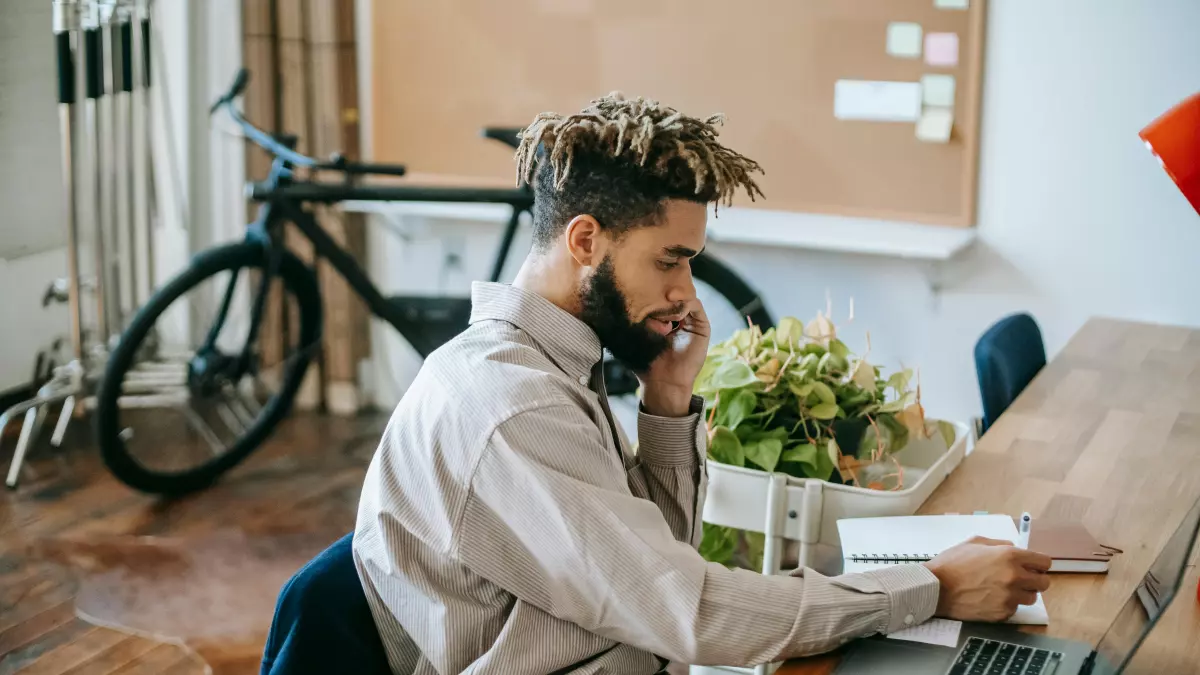 A person is working on a laptop while on a phone call.