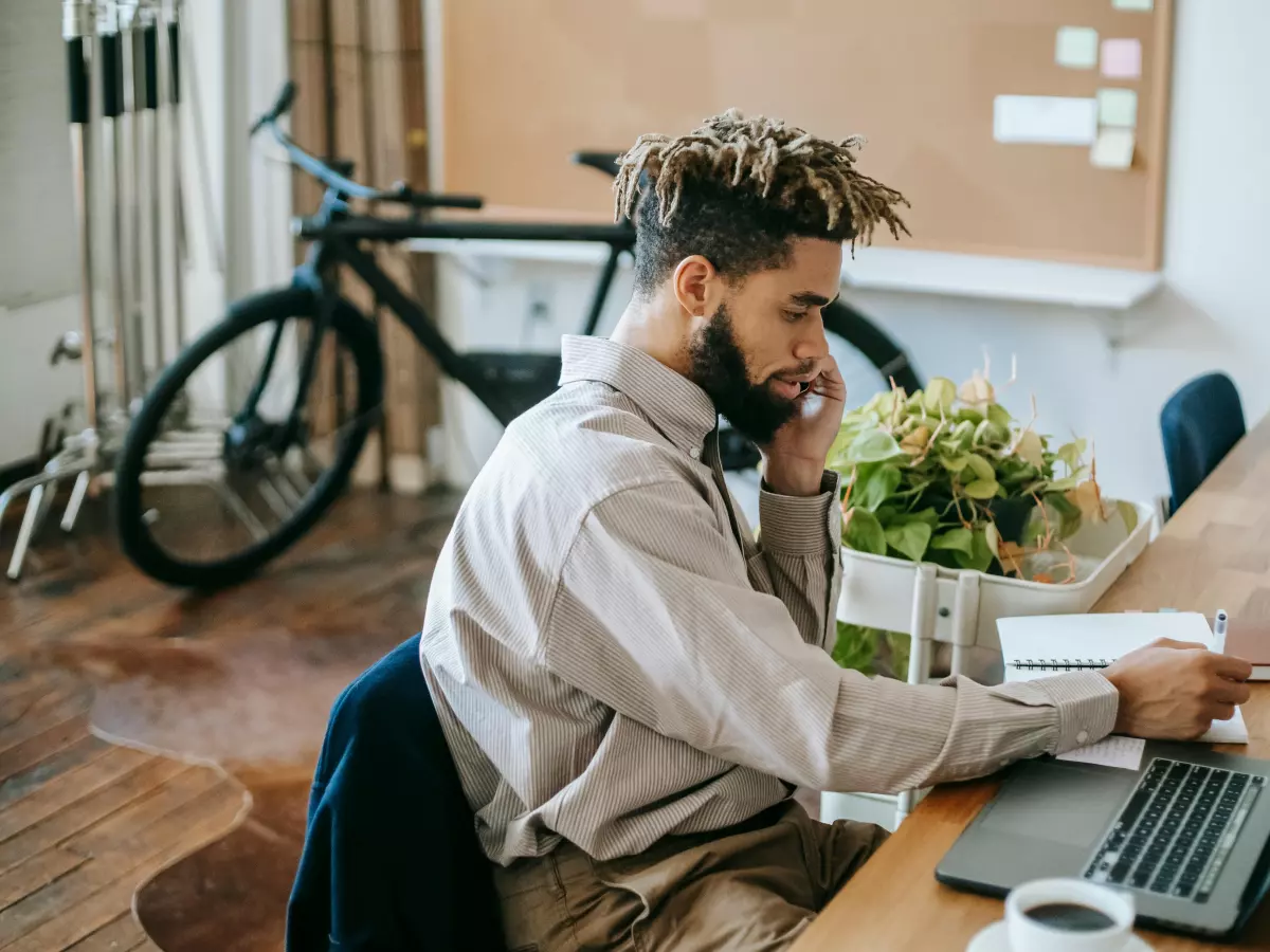 A person is working on a laptop while on a phone call.