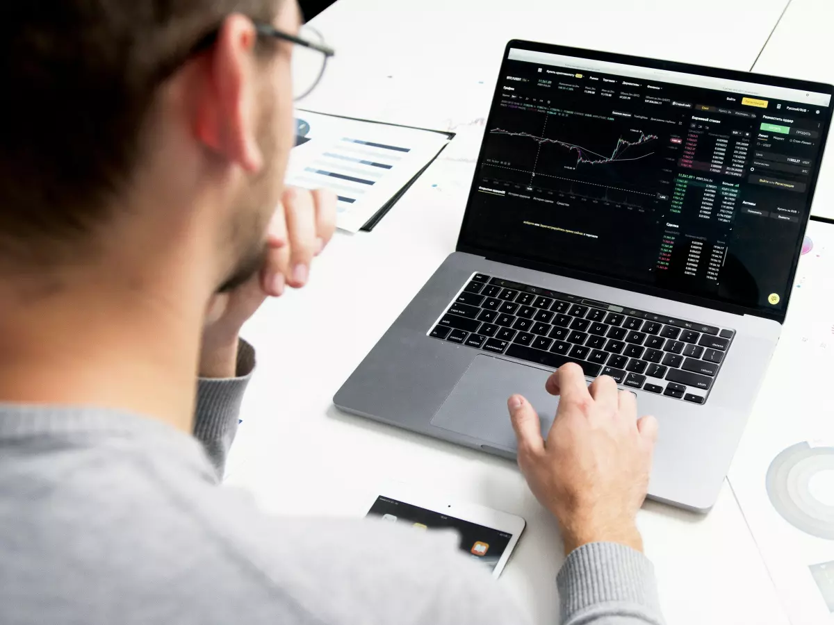 A person is looking at a laptop screen with stock market data on it.