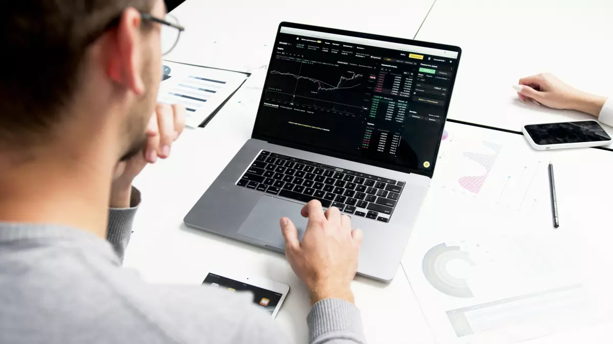 A person is looking at a laptop screen with stock market data on it.