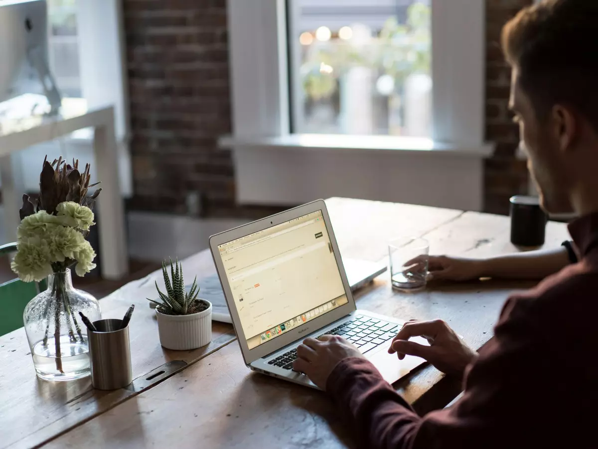 A person sitting at a table with a laptop in front of them. 