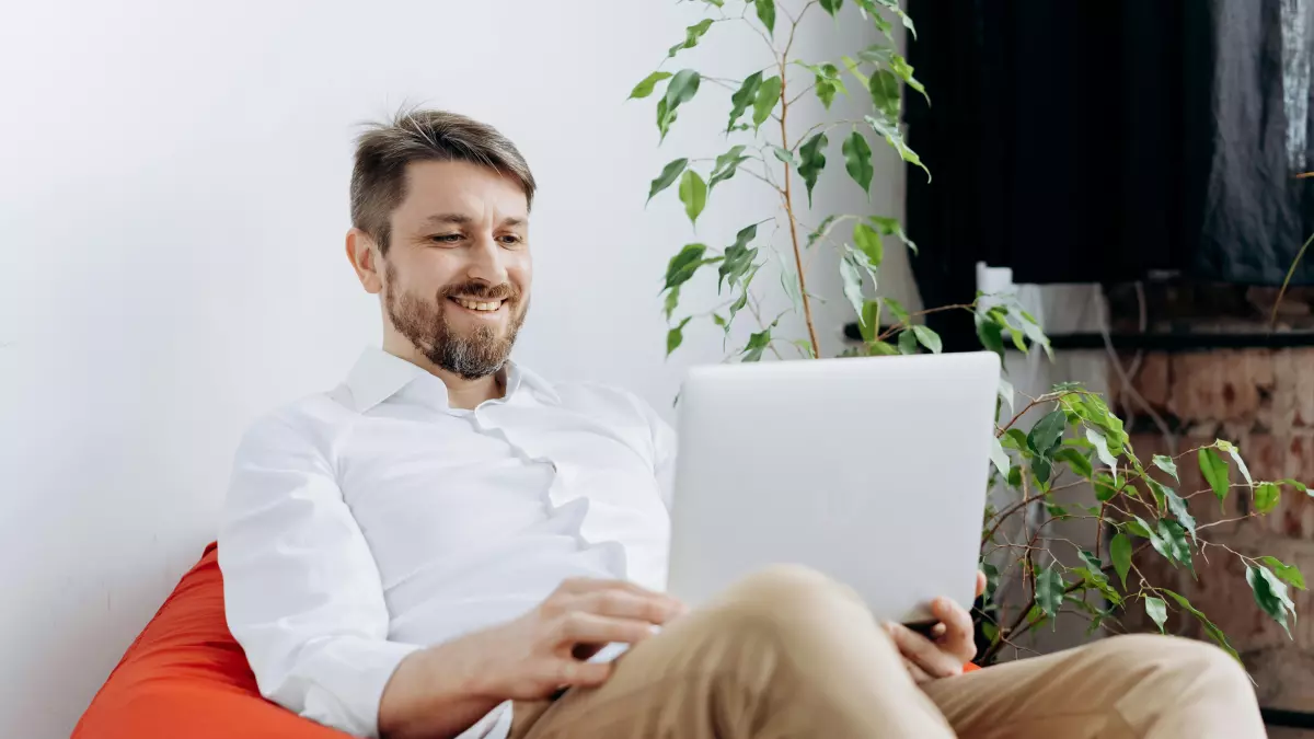 Two young men sitting on a bench, looking at a laptop together. They appear to be sharing a positive experience.