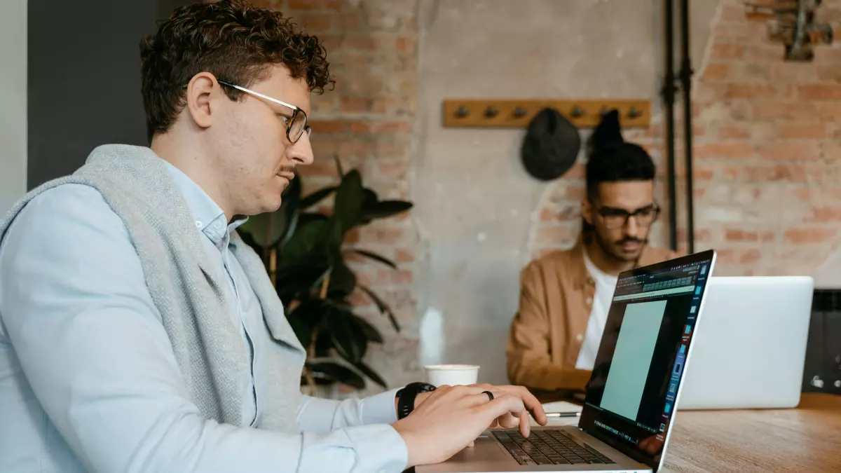 Two men working on laptops at a table.