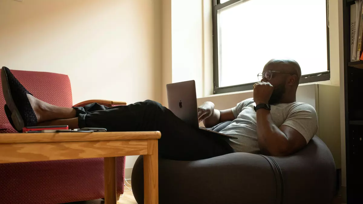 A person working on a laptop, sitting at a desk, with a cup of coffee and other office supplies.