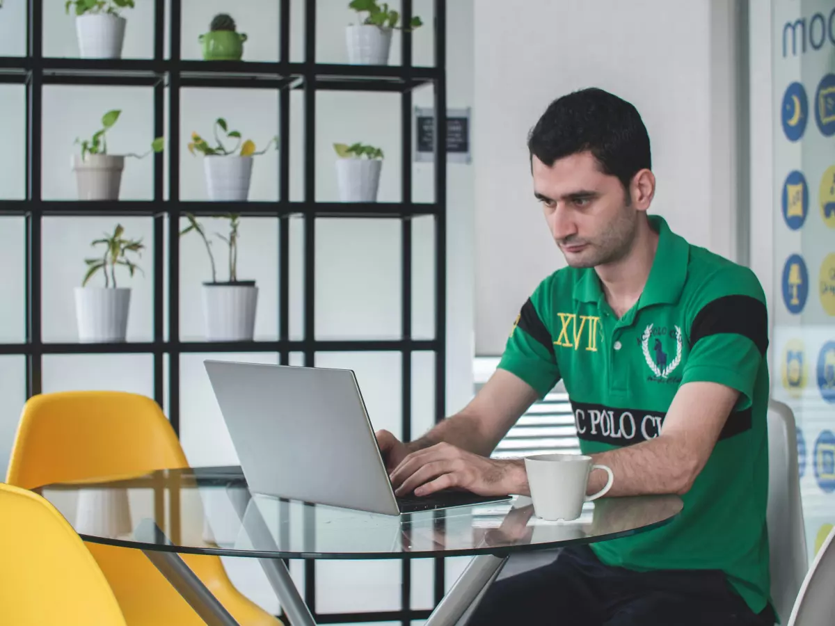 A man sitting in a chair with a laptop in front of him, in a professional setting. 