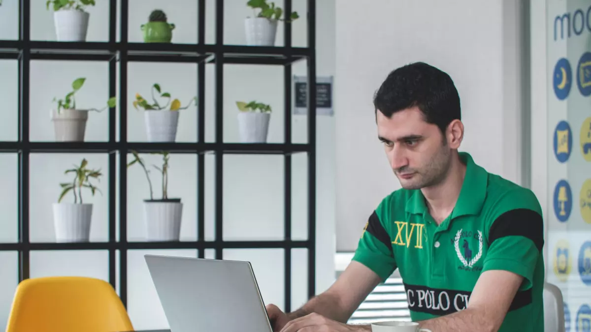 A man sitting in a chair with a laptop in front of him, in a professional setting. 