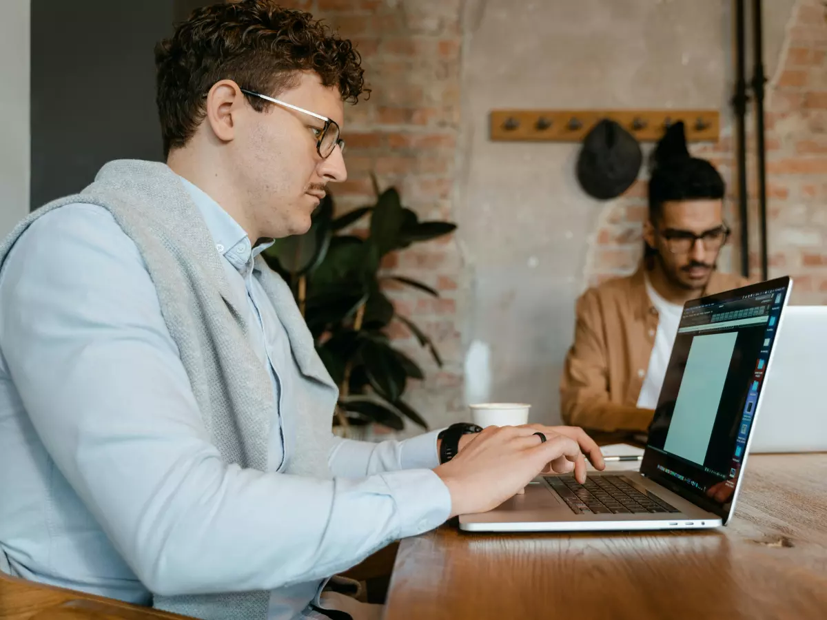 Two men working on laptops at a table.