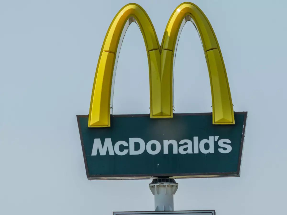 A close-up shot of the iconic McDonald's golden arches sign against a blue sky.