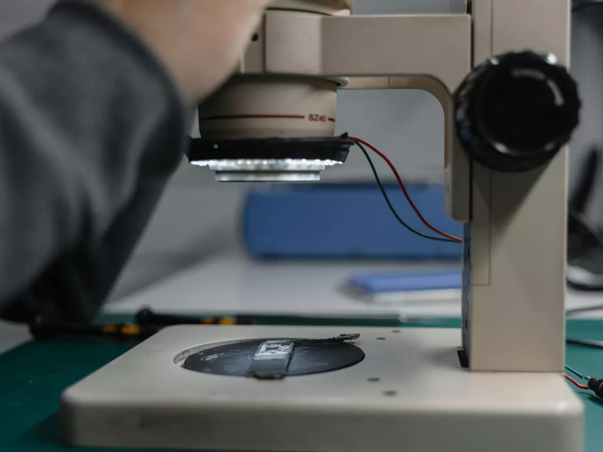 A person working on a small component under a microscope.