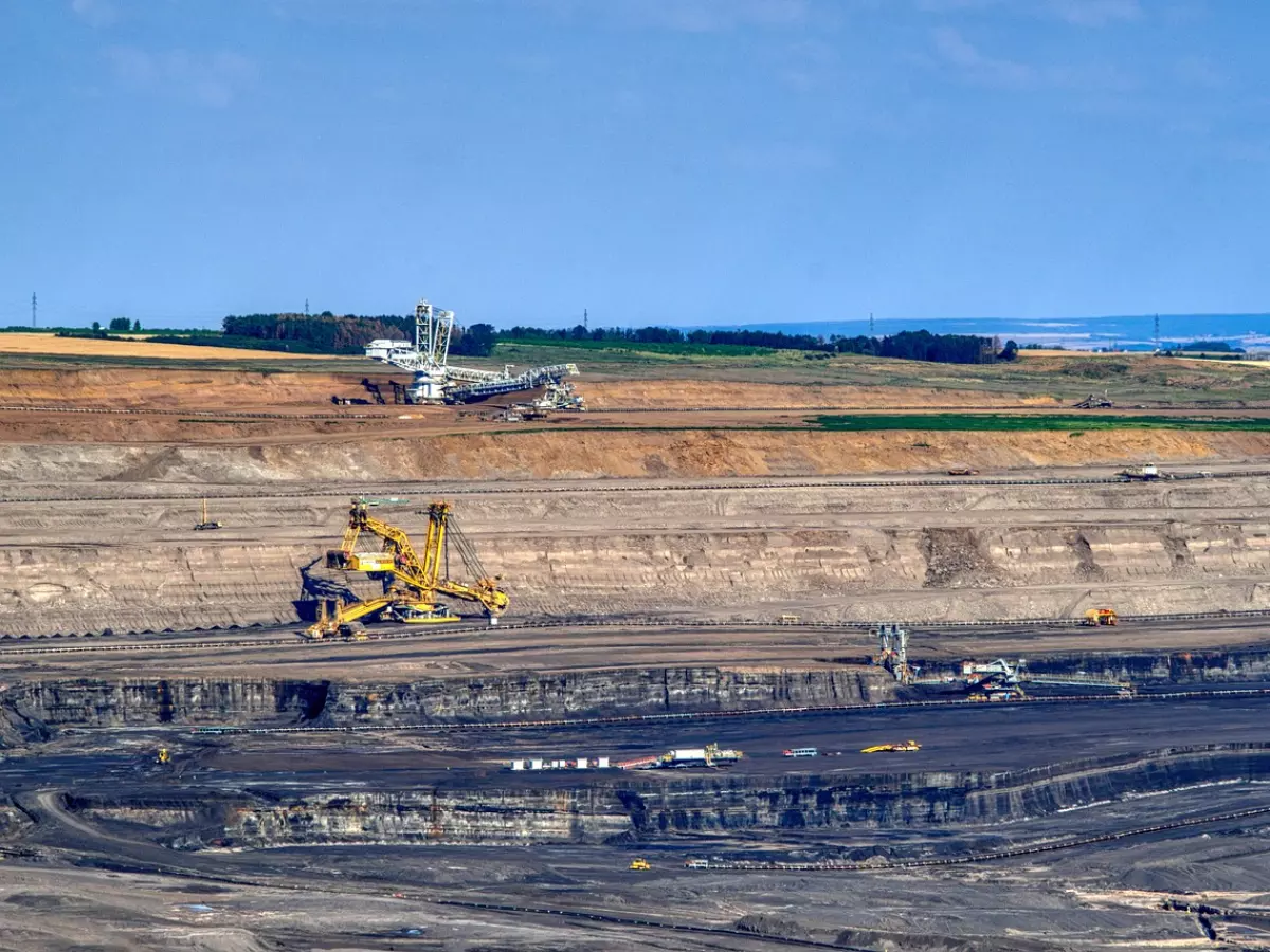 A large mining operation with multiple machines and vehicles. The image is taken from a high vantage point.