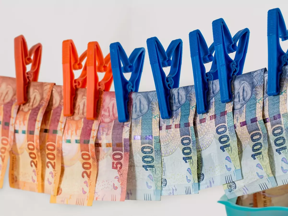 Several South African bank notes are hung on a clothesline, creating a dramatic and symbolic image of money laundering.