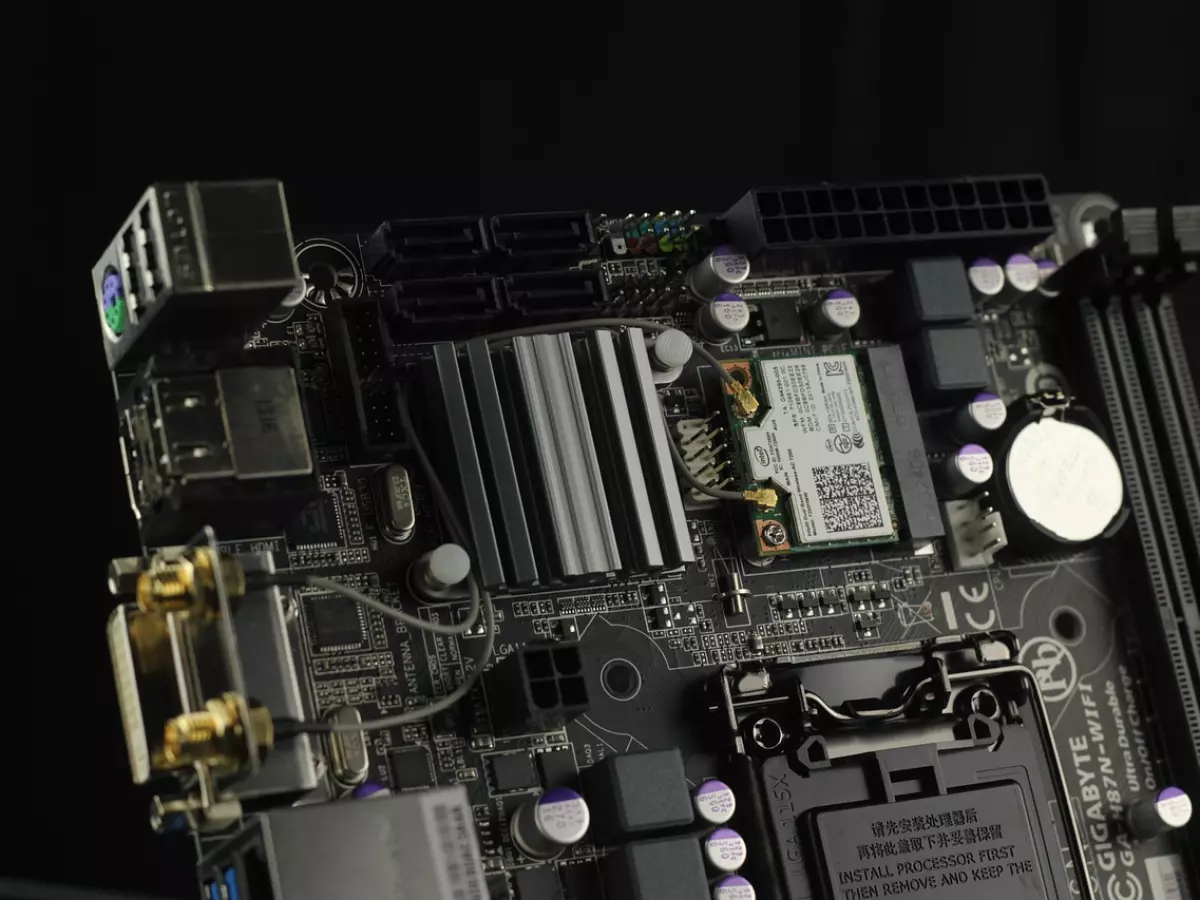 A close-up image of a motherboard with various components, including a WiFi chip and a connector for a USB device. The image is shot on a black background.