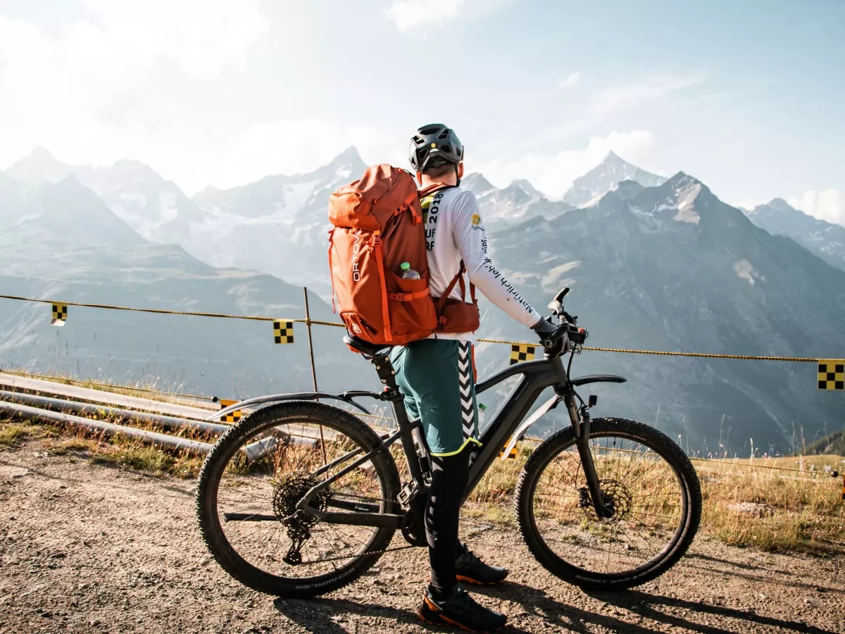 A person riding a mountain bike on a dirt path with a mountain background.