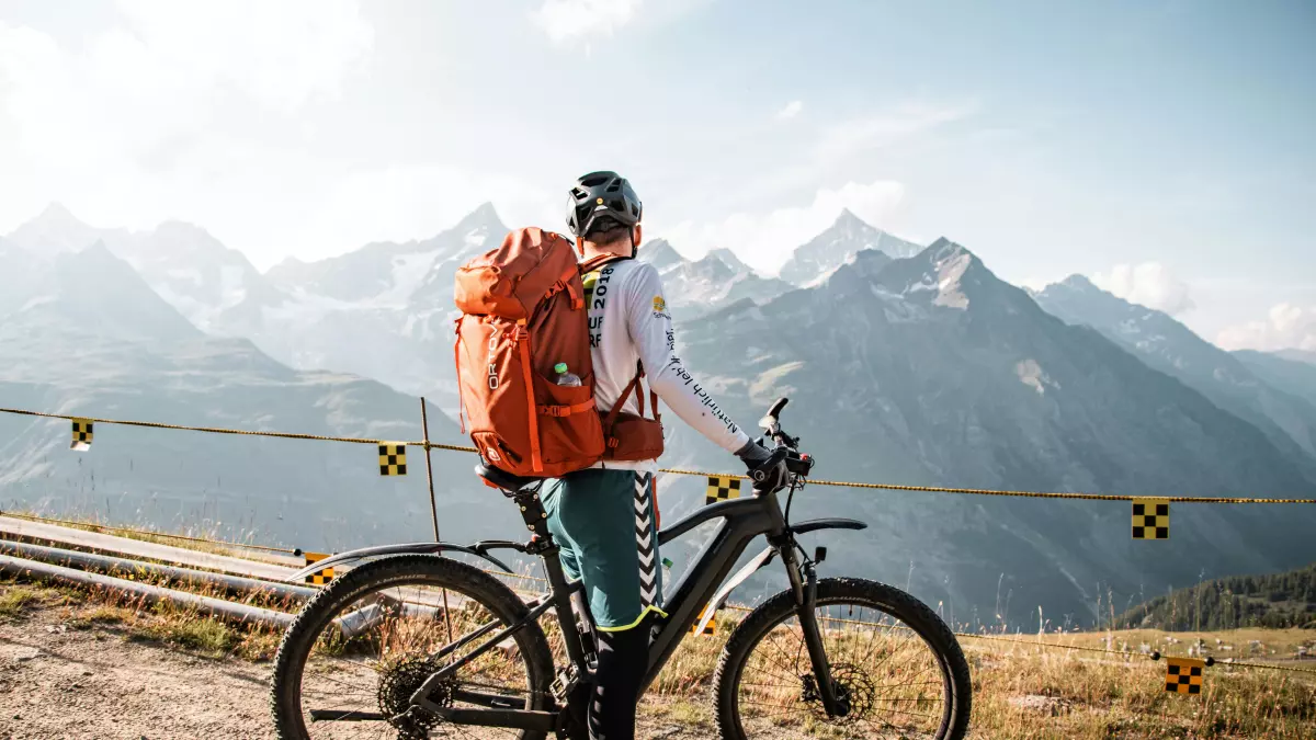 A person riding a mountain bike on a dirt path with a mountain background.