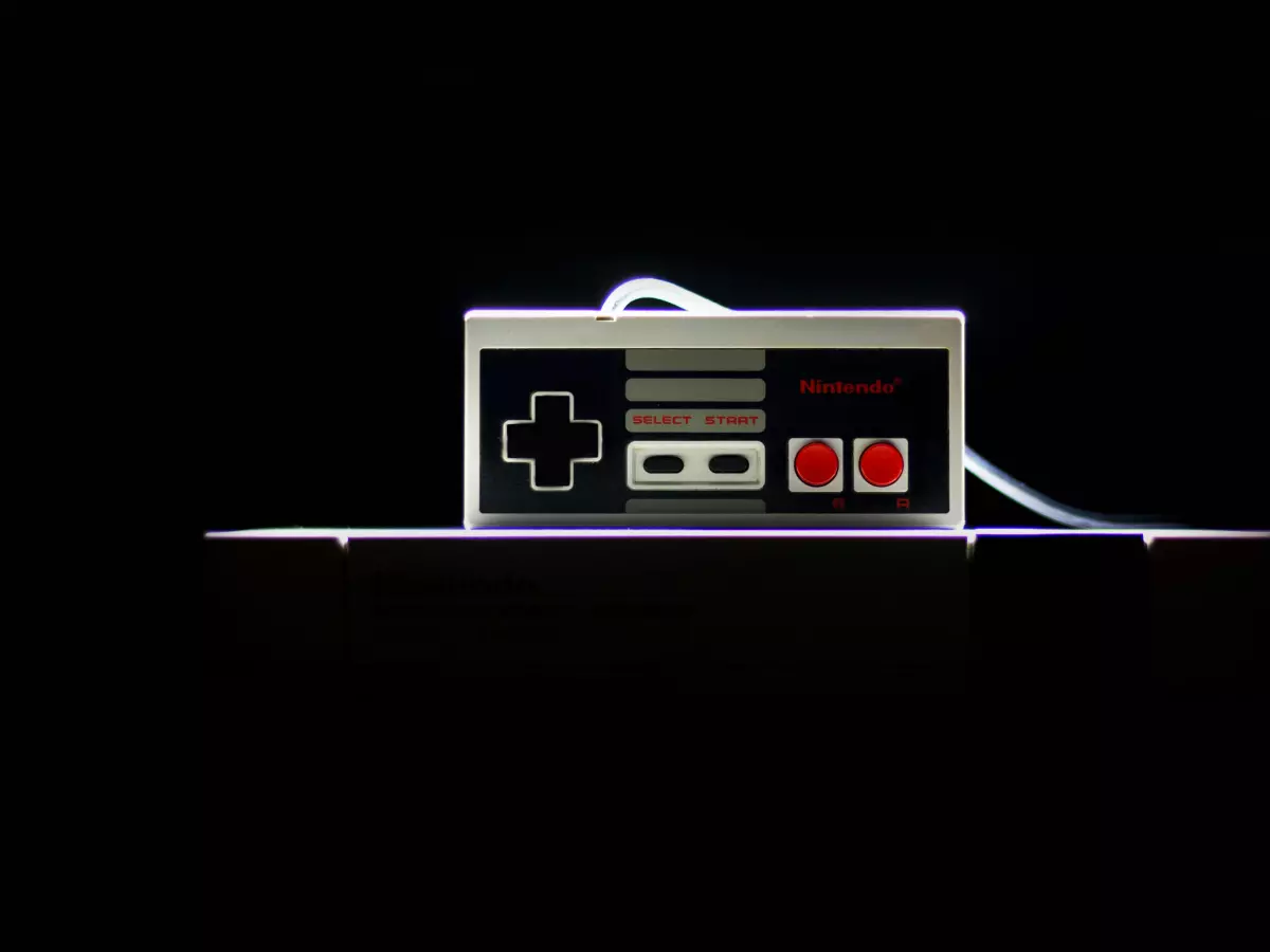 An iconic NES controller illuminated in a dark environment, highlighting its classic design with a dramatic lighting effect.