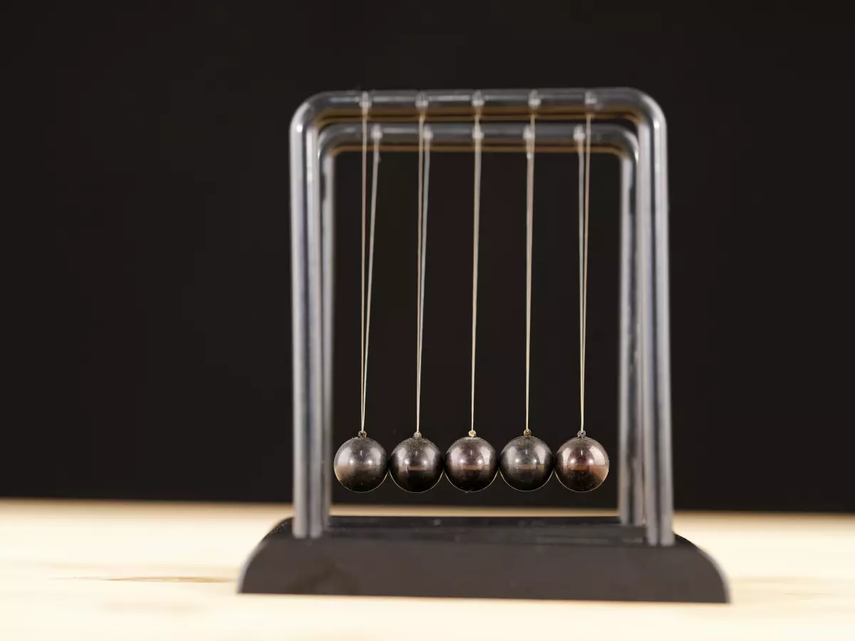 A Newton's cradle in motion against a dark background.