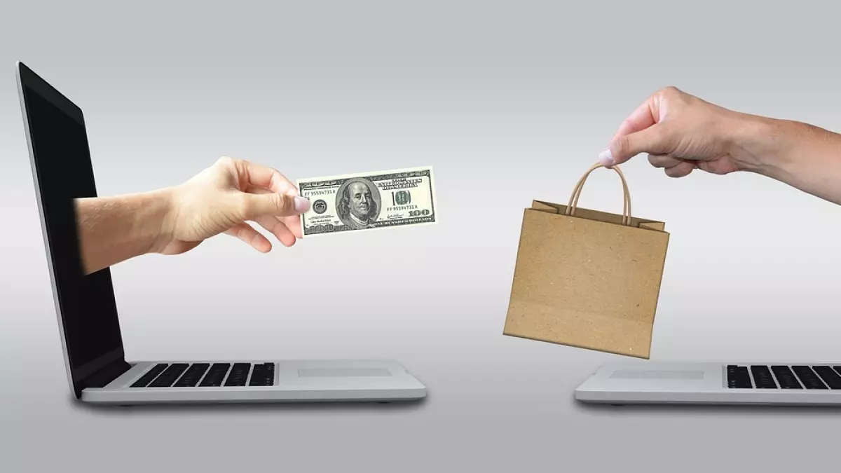 Two hands are reaching out of laptop screens. One hand is holding a $100 bill and the other hand is holding a brown paper bag.