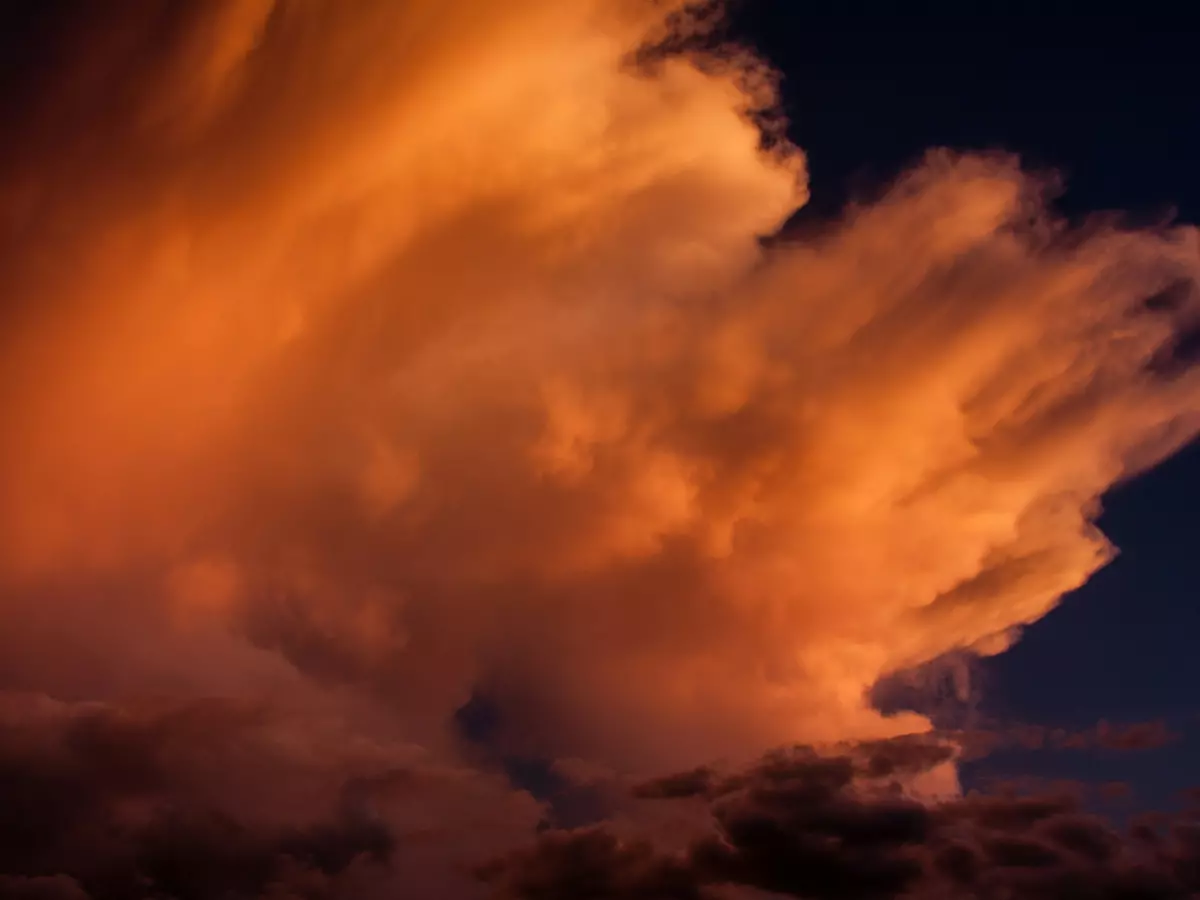 Close-up of a fiery red cloud against a dark blue sky.