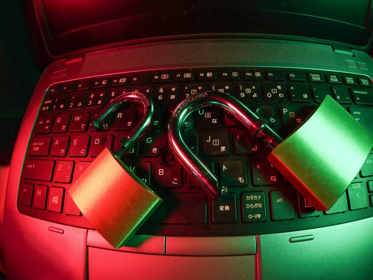 Two padlocks on a laptop keyboard, one red and one green, with a red and green light in the background.