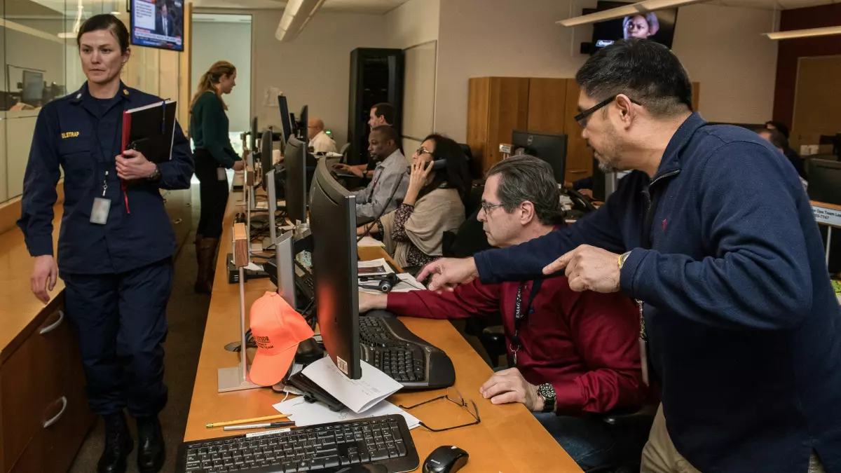 People working at computer terminals in a control center.