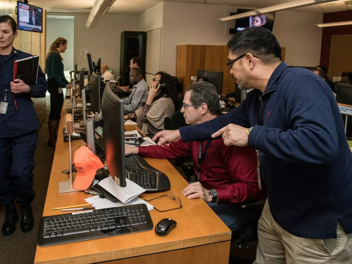 People working at computer terminals in a control center.