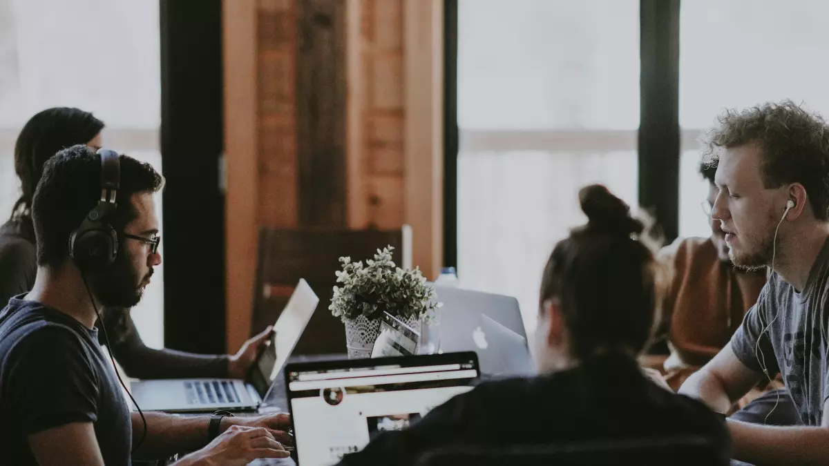 A group of people working on laptops in an office setting.