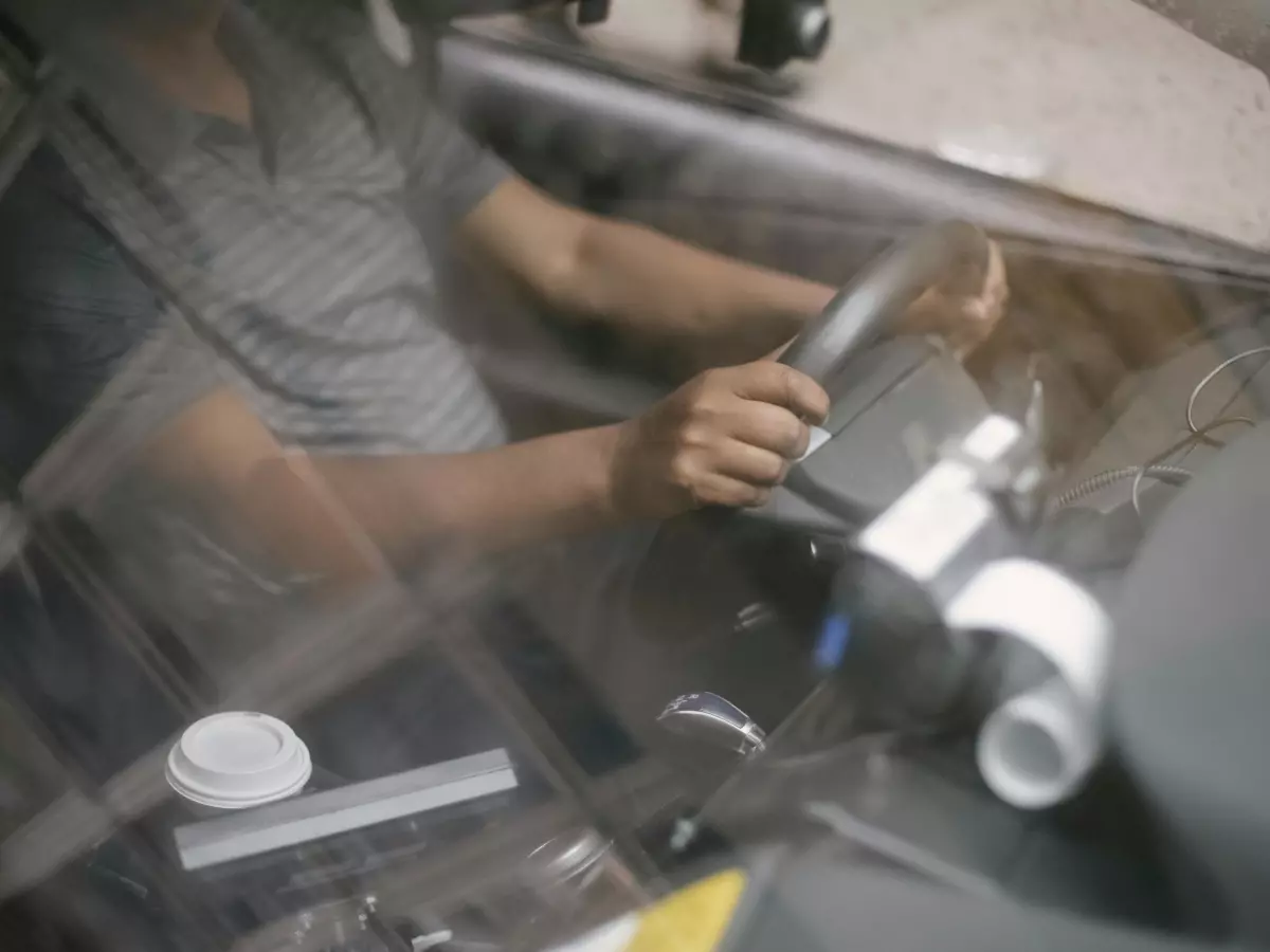 A man driving a car, with a GPS device in the foreground.