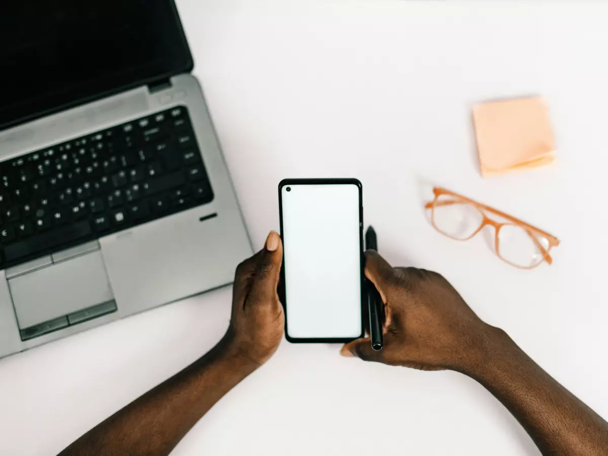 A person is holding a smartphone with a blank screen in their hands.