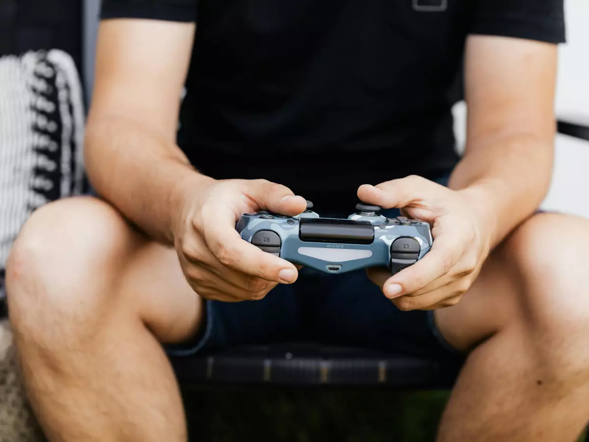 A person holding a PS5 controller, focusing on the hand.