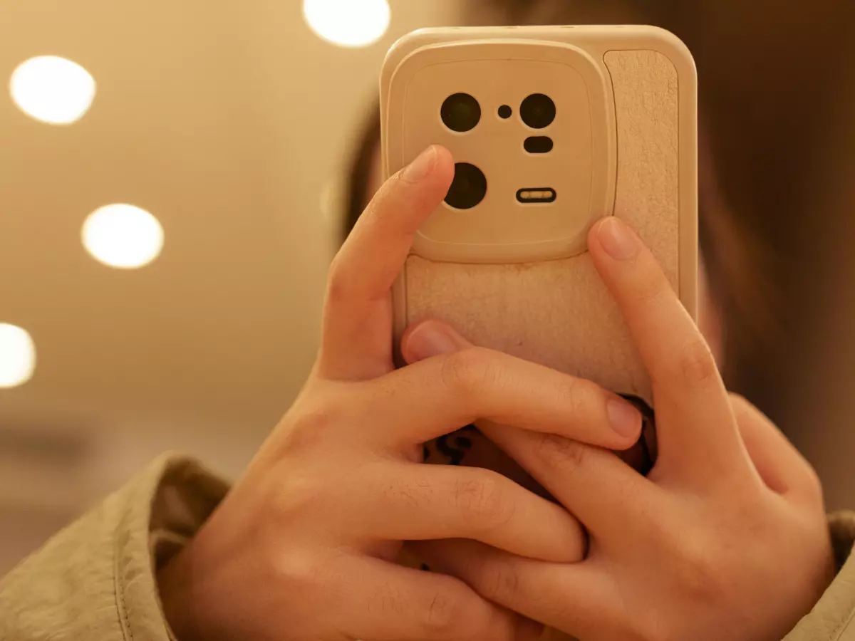 Close-up of hands holding a gold smartphone, focusing on the interaction between the fingers and the phone's surface.