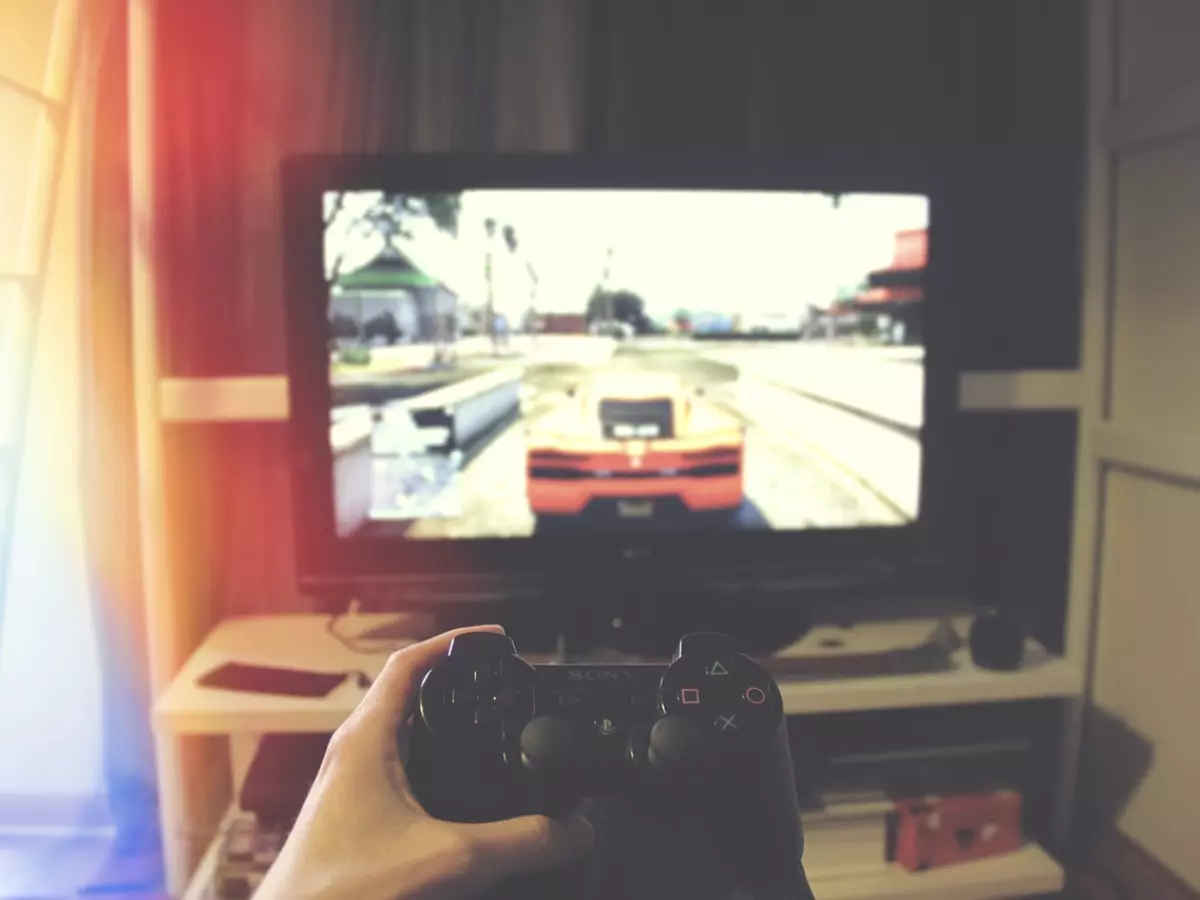 A person is playing a game on a console connected to a TV. The game is a racing game. The person is holding a controller and the image is taken from the perspective of the player.