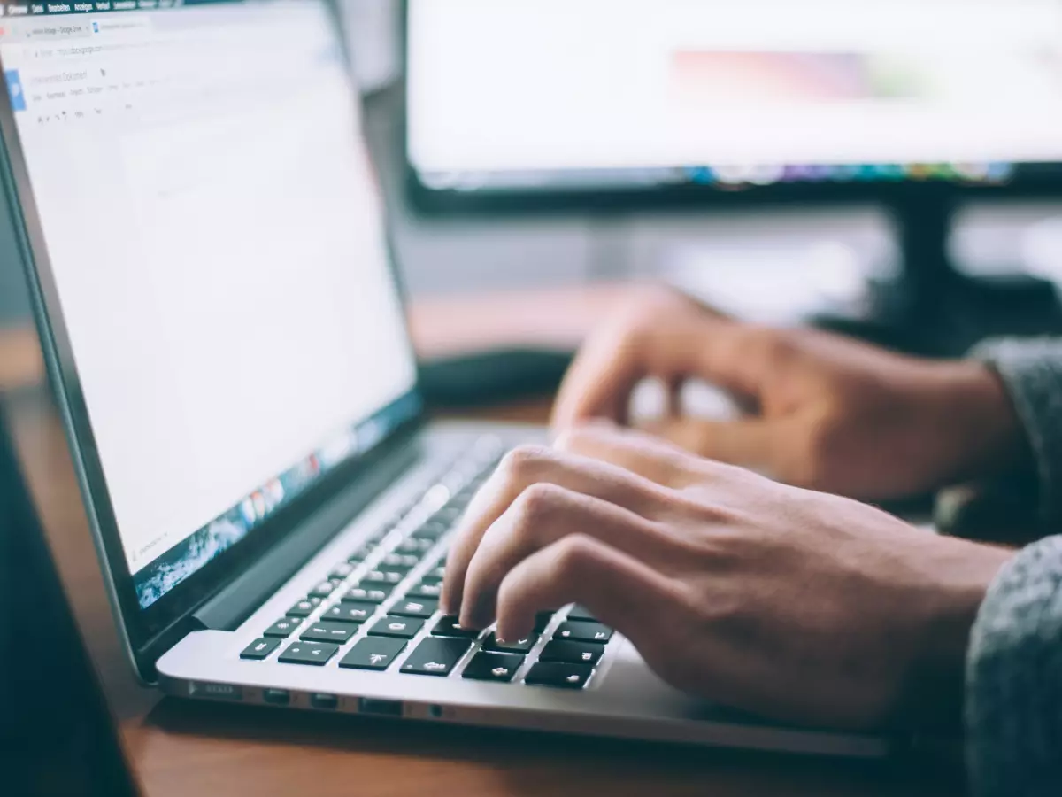 Close-up shot of a person typing on a laptop keyboard.