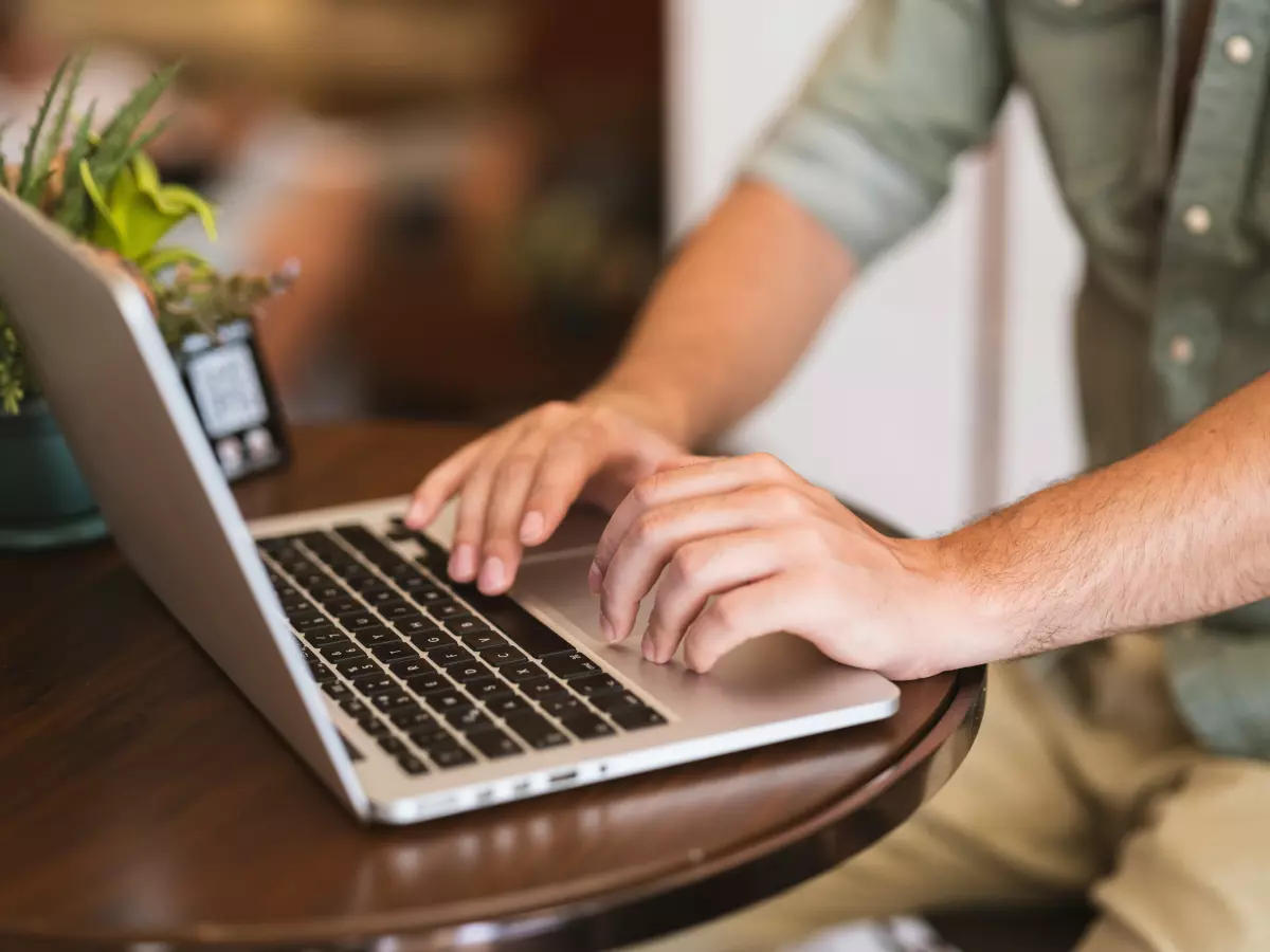 A person is using a laptop at a table in a coffee shop. 