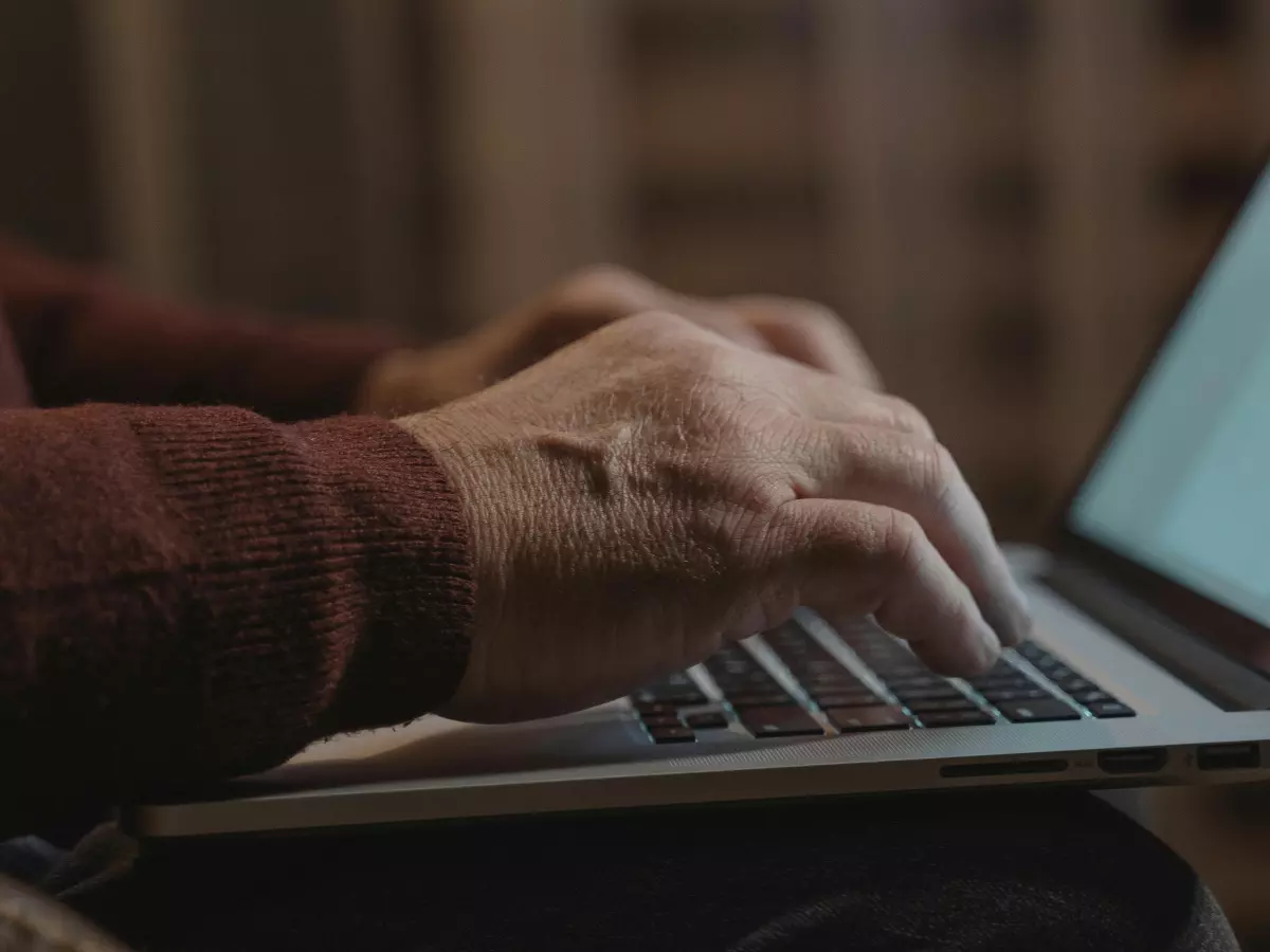 A person typing on a laptop, their hands and posture suggesting focus and effort.