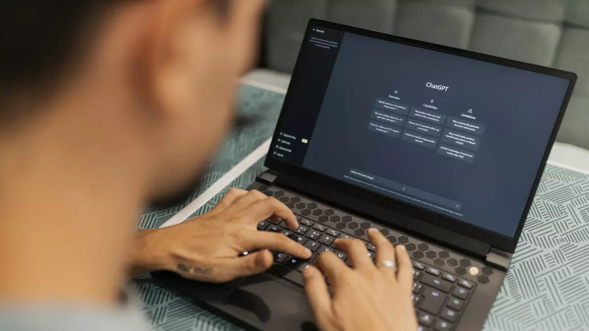 A person working on a laptop, with their hands on the keyboard and the screen visible in the background.